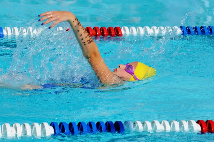 Close-up of a female backstroke swimmer recovering her arm forward.