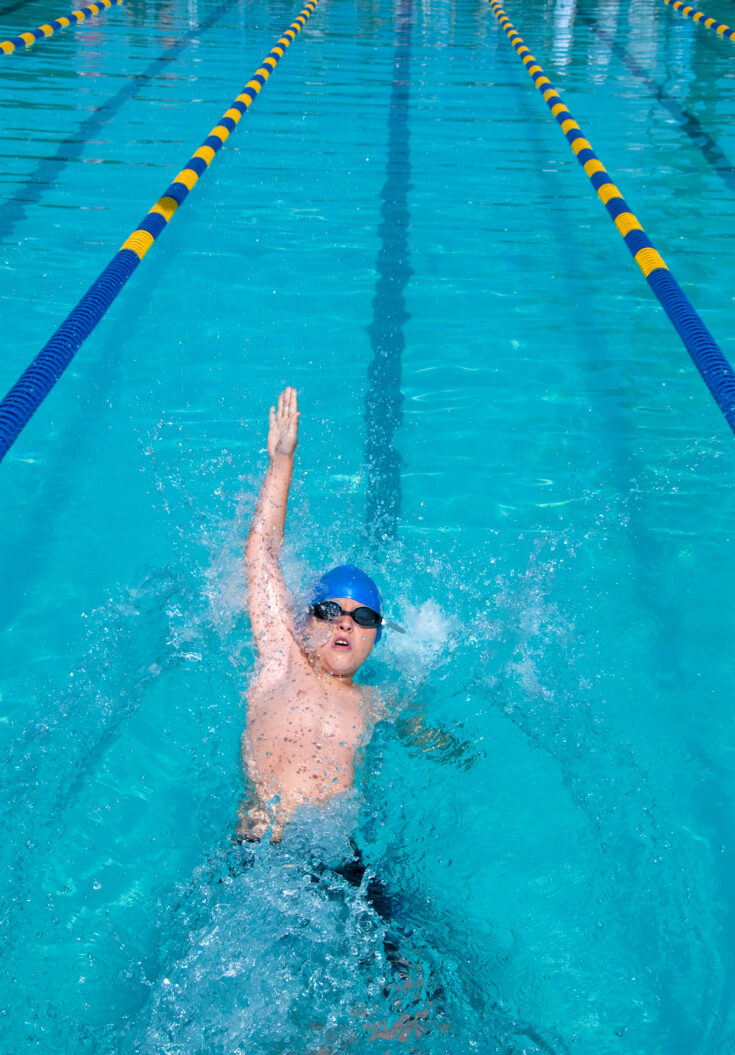 A young boy swimming backstroke