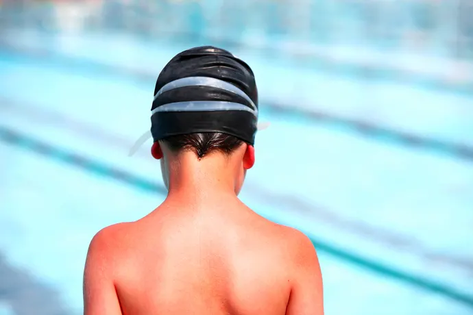 A young boy swimmer with a sunburned back and shoulders