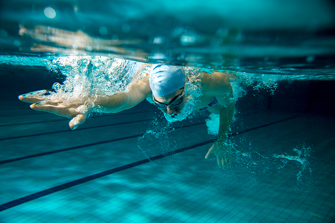 Close-up of the face of a freestyle swimmer while he exhales in the water.