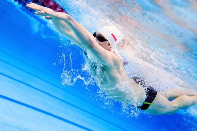 Underwater shot of a butterfly swimmer at the end of the arm recovery forward.