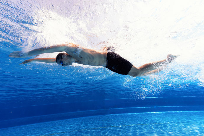 A butterfly swimmer underwater, seen from the side.