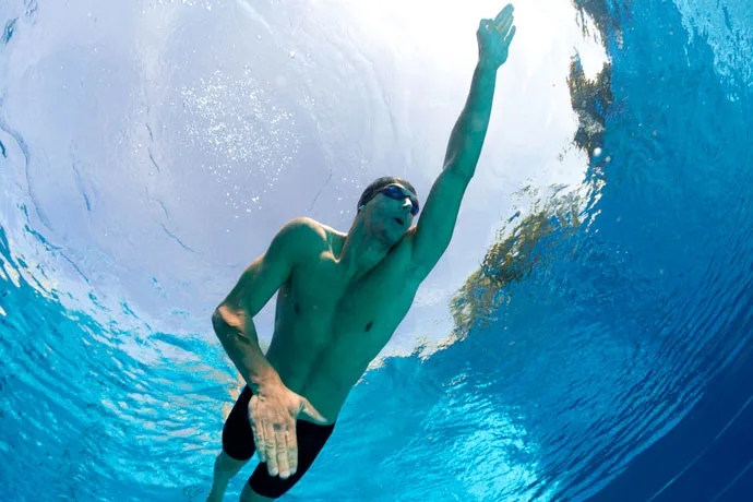 Underwater shot of a male front crawl swimmer where the arm movements are the focus.