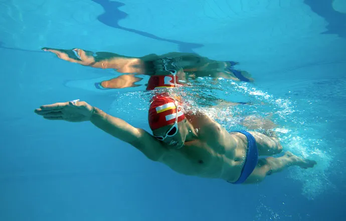A front crawl swimmer having one arm fully extended forward in the water and the other arm recovering above the water.