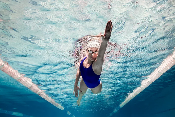 A female front crawl swimmer gliding on the left side of her body.
