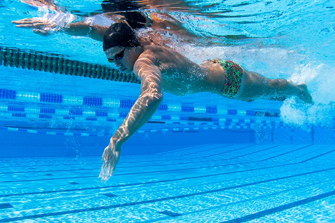 A young man swimming front crawl and using a high-elbow catch.