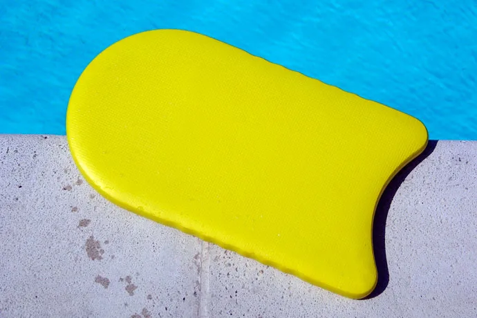 A kickboard lying on a pool's wall