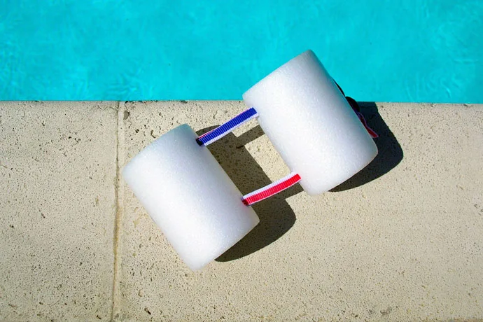 A two-piece pull buoy lying on the edge of the pool