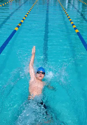 A child swimming backstroke and headed towards the wall.
