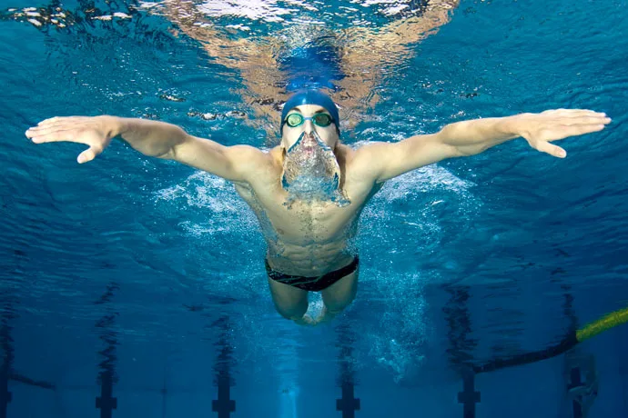 A butterfly swimmer exhales in the water.