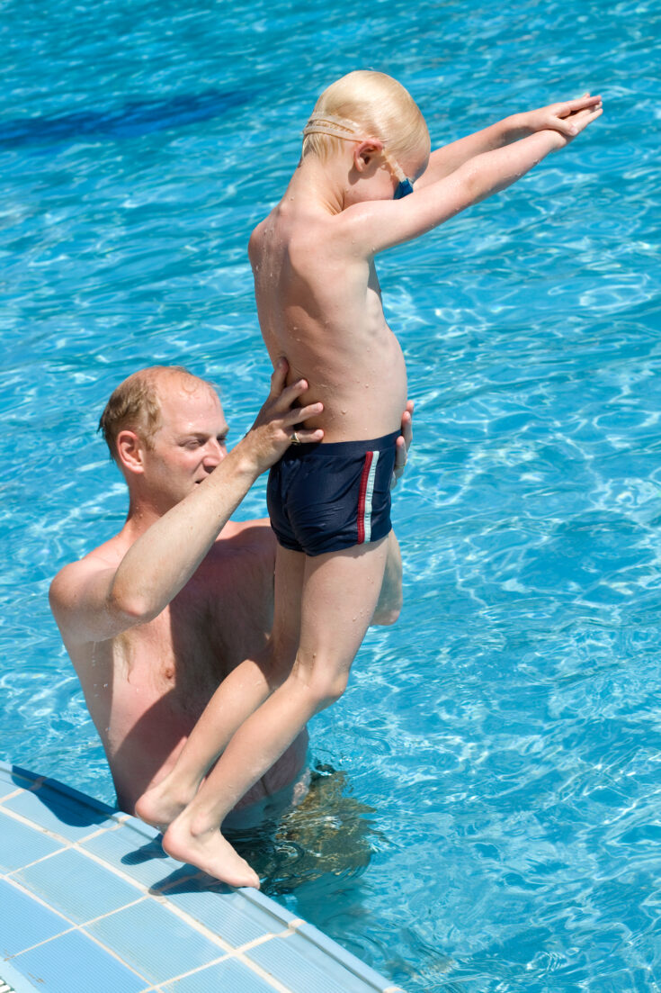 A swim class where a swim instructor teaches a child how to dive