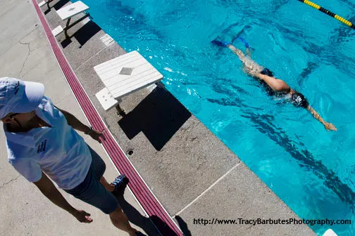 A swim instructor watching a student executing a swimming drill
