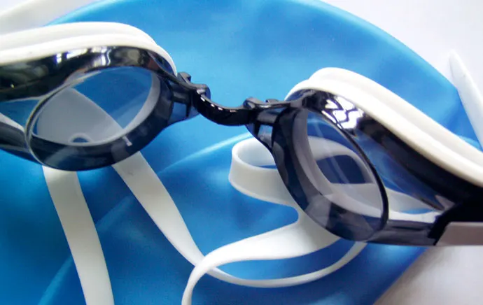 A pair of swimming goggles lying on a swim cap.
