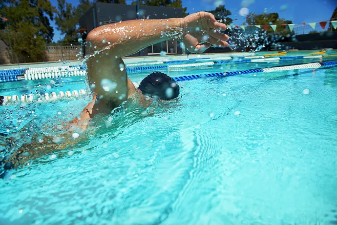 A front crawl swimmer swimming outside in an outdoor pool