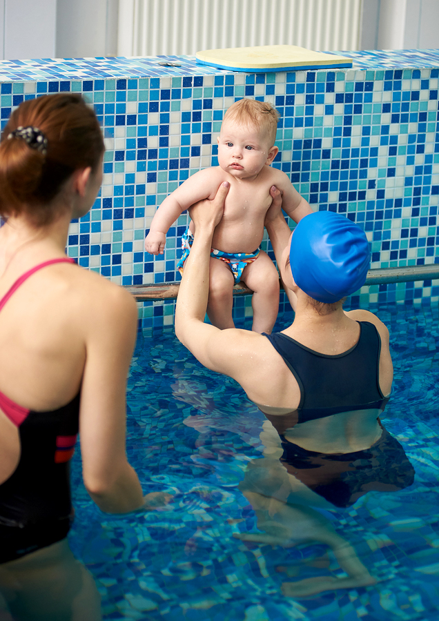 A mother and her child taking baby swimming lessons.