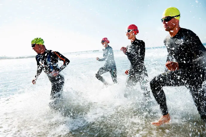 triathlon training - triathletes running toward the water