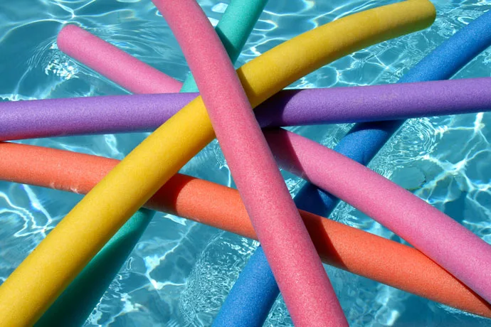 A few colorful swimming noodles floating on the water surface